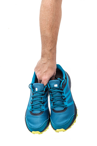 Pair of trail-running sneakers in a male hand isolated on white background