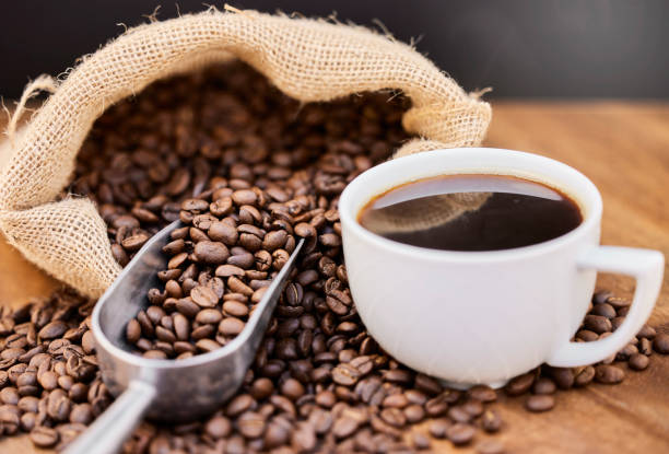 ภาพเมล็ดกาแฟและกาแฟดําหนึ่งถ้วยบนโต๊ะไม้ - กาแฟ ภาพสต็อก ภาพถ่ายและรูปภาพปลอดค่าลิขสิทธิ์