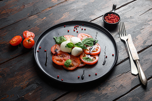 Tomato, basil, mozzarella Caprese salad with balsamic vinegar and olive oil. old wooden planks  background.