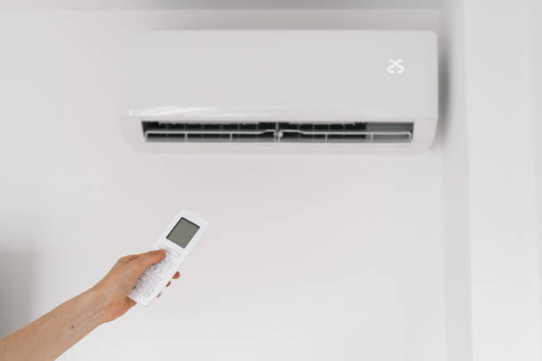 istock Woman holding remote controller against air conditioner 1349246517