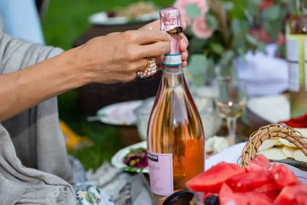 Babyshower picnic on the air park women hands open bottle of wine with big ring