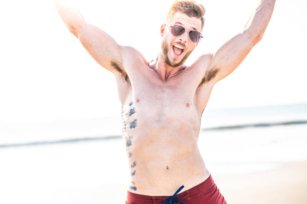 istock Expressive fit young man in sunglasses jumping for joy on an idyllic beach 1349257058