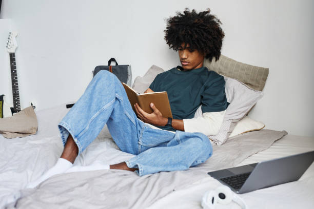 istock Teenage Boy Sitting on Bed 1349258064