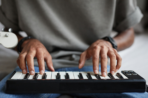 Close up of young African-American musician composing music, focus on hands at DJ keyboard, copy space