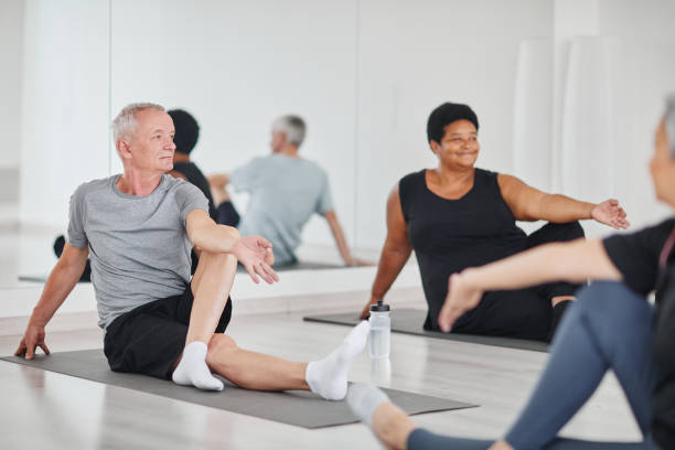 älterer mann, der yoga im unterricht praktiziert - senior adult sport yoga exercising stock-fotos und bilder