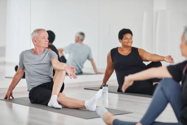 uomo anziano che pratica yoga in classe - gym women inside of exercising foto e immagini stock