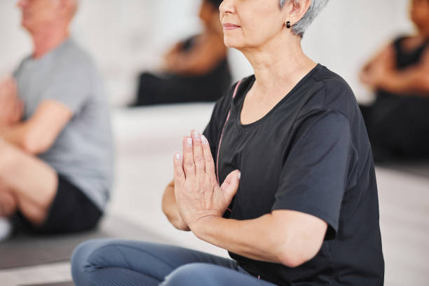 mujer mayor meditando durante el entrenamiento - women yoga yoga class mature adult fotografías e imágenes de stock