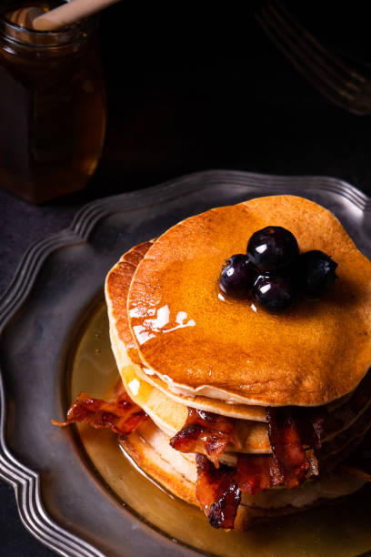 istock Fresh homemade pancake stack with crispy organic bacon and blueberry fruit butter drippings honey maple syrup for tasty sweet morning breakfast with American traditional authentic style 1349267965