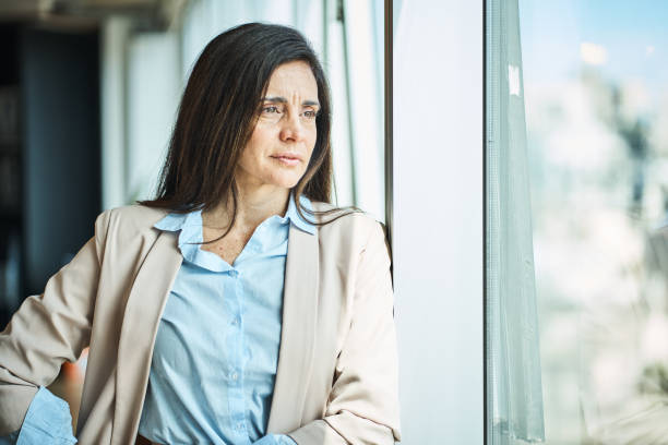 istock Thoughtful mature businesswoman standing by window 1349268436