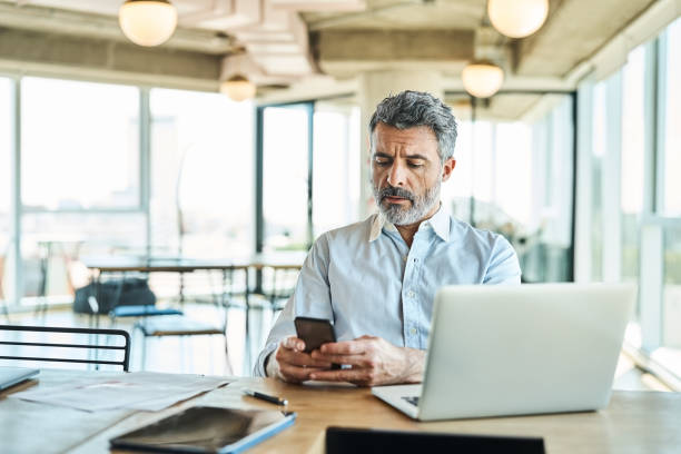 istock Mature businessman using smart phone in office 1349268447