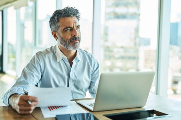 Businessman with report looking away and thinking at office