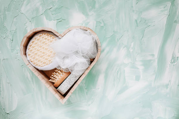Bath kit in heart shaped wooden box on green background. Beauty, spa at home and bath concept. Top view, copy space