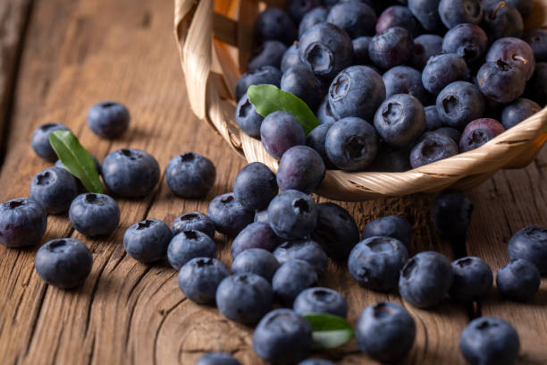 arándanos en cesta sobre mesa de madera - blueberry fotografías e imágenes de stock