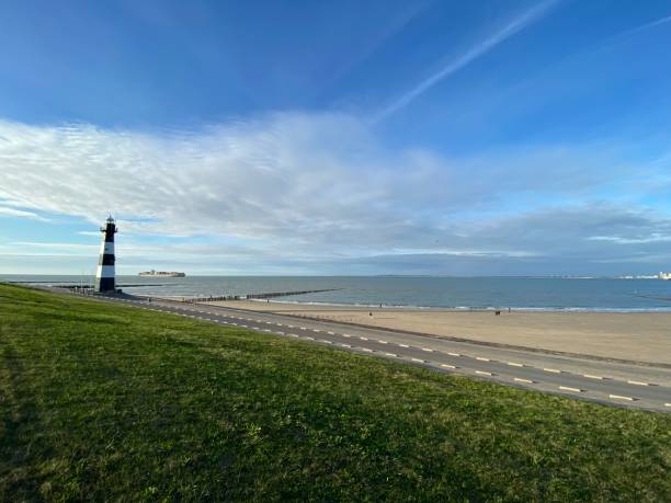 istock Black and white striped lighthouse by the sea 1349284485