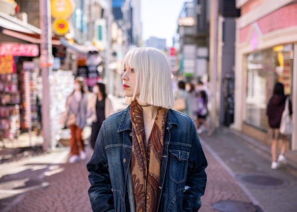 Young woman with platinum blonde hair walking on shopping street Young multiracial woman with platinum blonde wig visiting Harajuku and take photos/videos for blogging/vlogging. tokyo harajuku stock pictures, royalty-free photos & images
