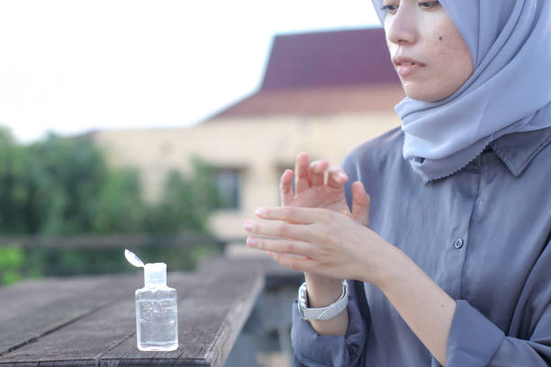 istock young women using hand sanitizer sitting at the park 1349291388