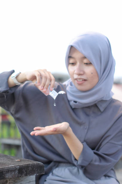 istock young women using hand sanitizer sitting at the park 1349291439