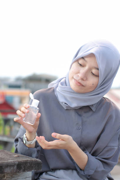 istock young women using hand sanitizer sitting at the park 1349292727