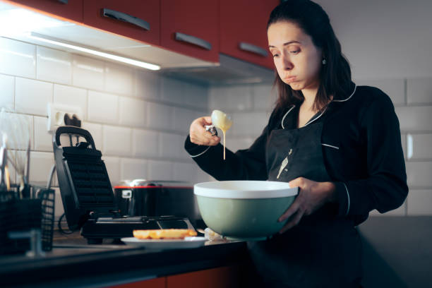 femme cuisinant le petit-déjeuner tachant son tablier avec un mélange de gaufres - cooking fail photos et images de collection