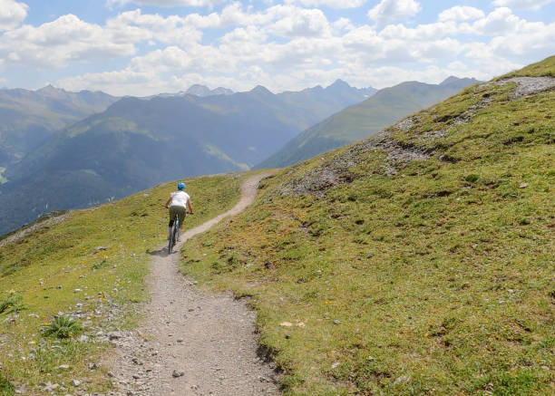 istock Female mountain biker follows trail down grass slope 1349295016