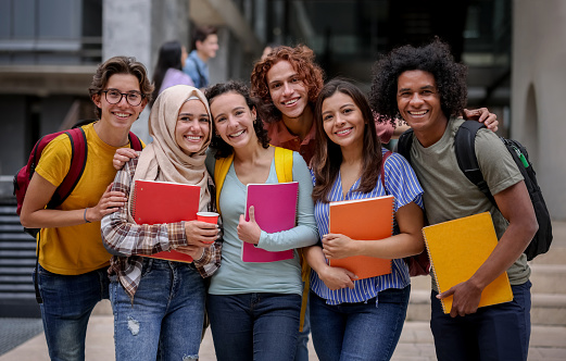 Multi-ethnic group of Latin American college students smiling at the university campus and looking at the camera - education concepts