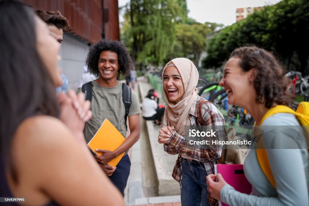 Multi-ethnic group of students looking happy talking at the school and laughing Multi-ethnic group of college students looking very happy talking at the school and laughing Student Stock Photo