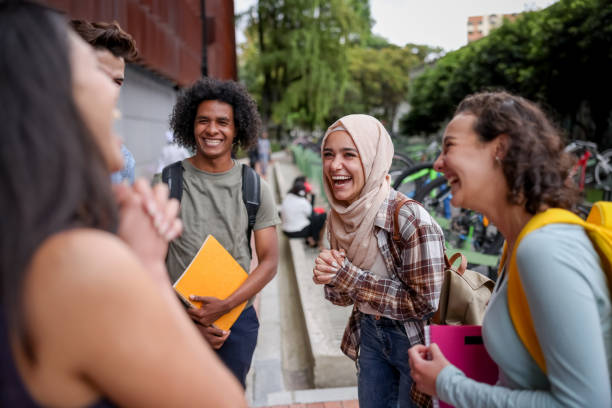 Multi-ethnic group of students looking happy talking at the school and laughing stock photo