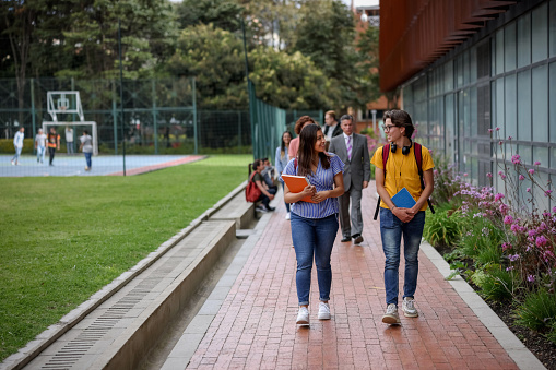 Happy Latin American college students talking at the university campus and smiling - education concepts