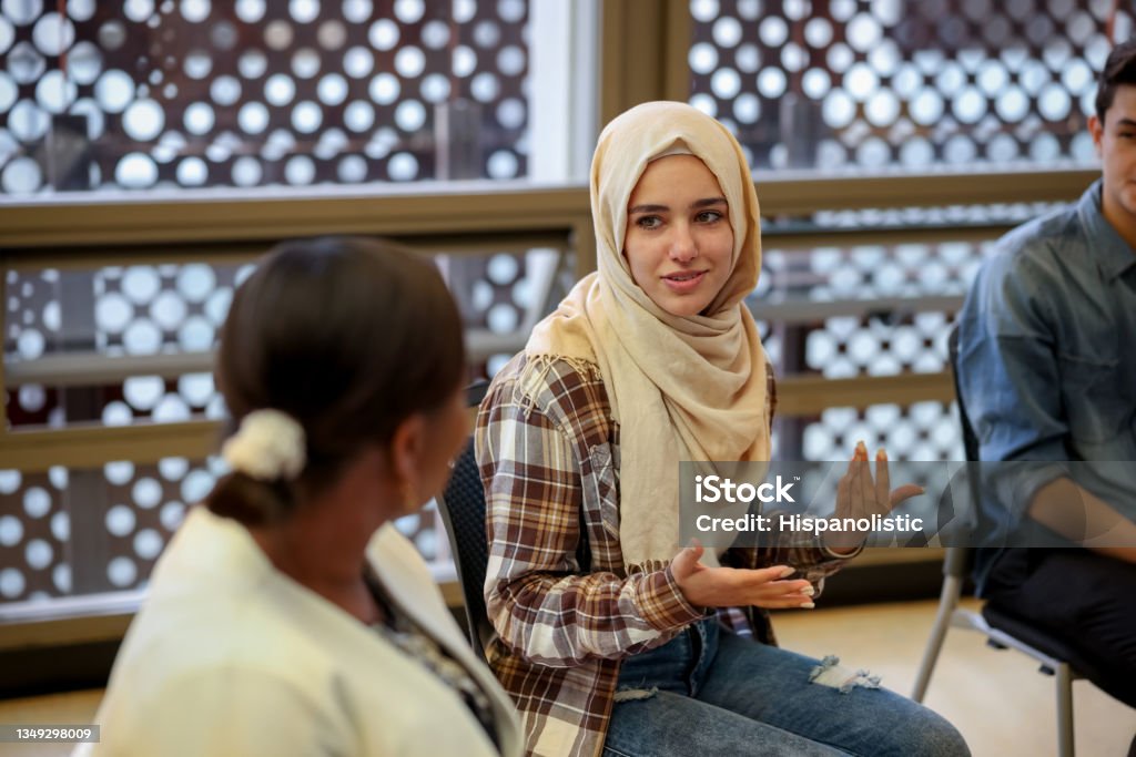 Muslim college students talking to a group in counseling Muslim college students talking to a group in a counseling session - mental health concepts Discussion Stock Photo