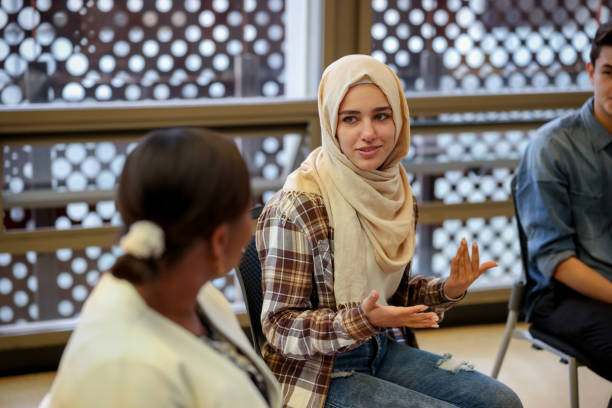 Muslim college students talking to a group in counseling Muslim college students talking to a group in a counseling session - mental health concepts hijab stock pictures, royalty-free photos & images