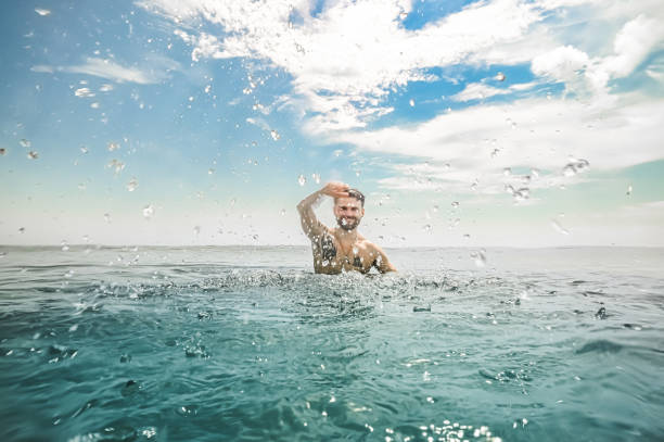 istock Man splashing water in idyllic blue ocean 1349298803