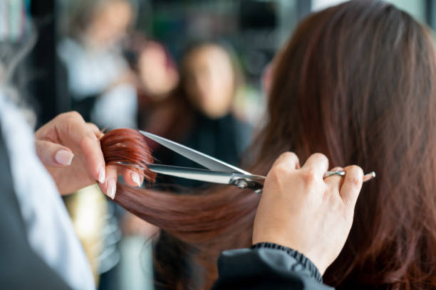 feche acima de cabeleireiro irreconhecível cortando um cabelo de clientes femininos - salão de beleza - fotografias e filmes do acervo