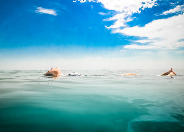 Pretty young woman floating in deep blue ocean