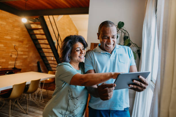 pareja madura usando tableta digital en casa. - 50 59 años fotografías e imágenes de stock