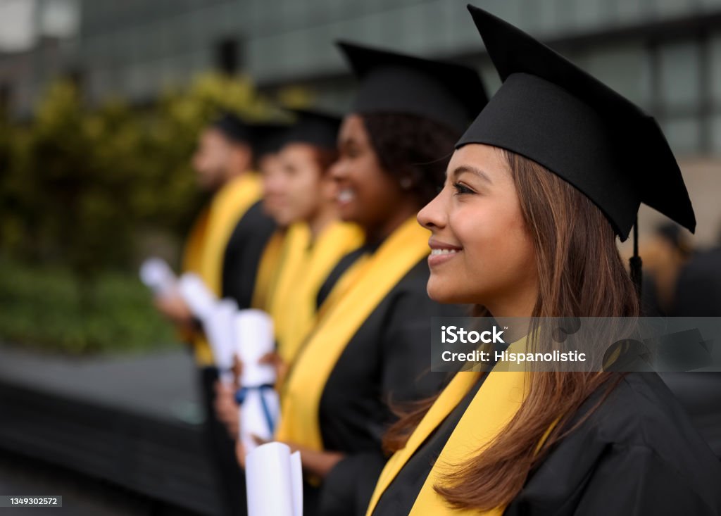 Happy group of graduate students in a row holding their diplomas Happy group of graduate students in a row holding their diplomas on their graduation day and smiling - education concepts Graduation Stock Photo