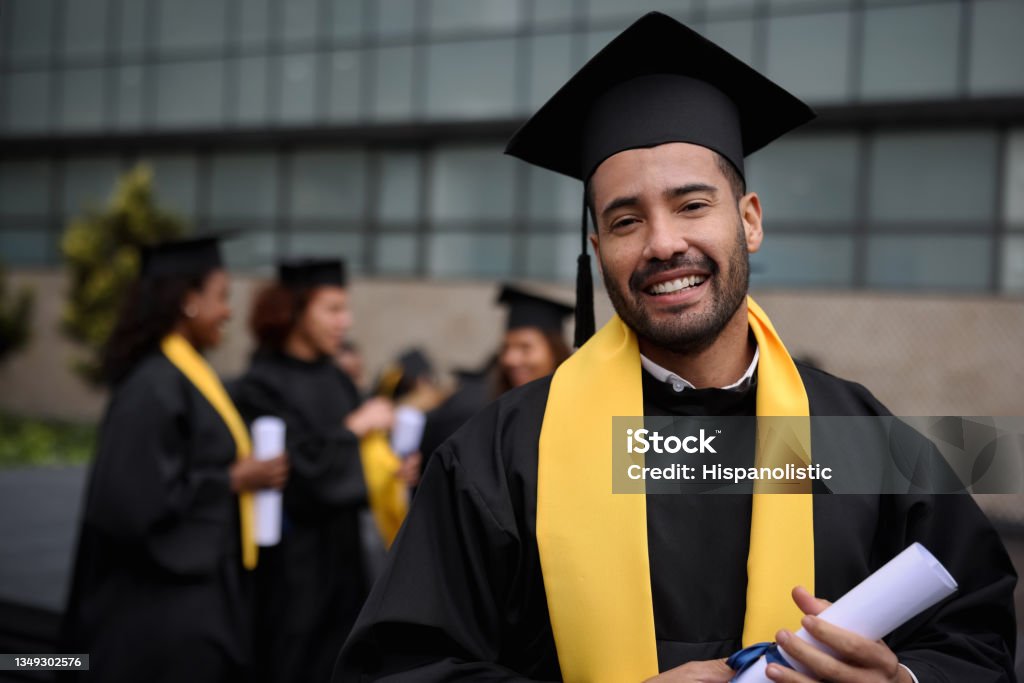 Happy graduate student holding his diploma on graduation day Portrait of a happy graduate student holding his diploma on graduation day and looking at the camera smiling - education concepts Graduation Stock Photo