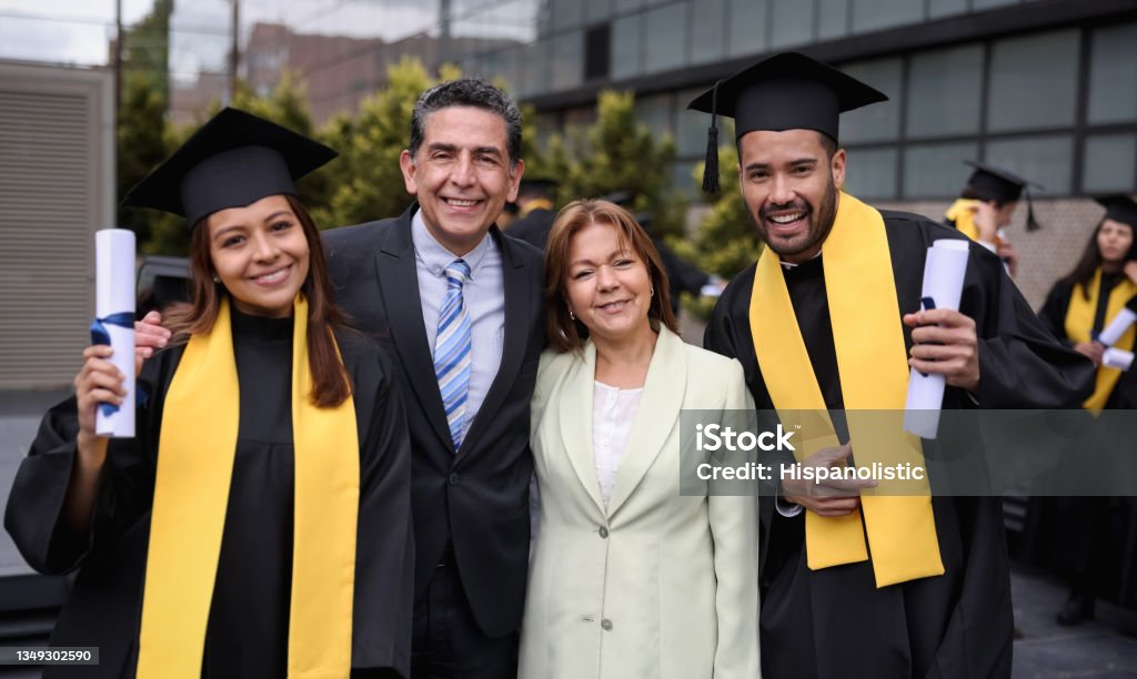 Graduate students smiling with their parents on their graduation day Portrait of happy Latin American graduate students smiling with their parents on their graduation day while looking at the camera - education concepts Graduation Stock Photo