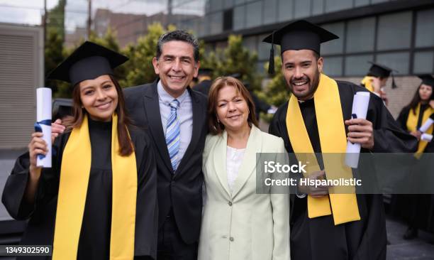 Graduate Students Smiling With Their Parents On Their Graduation Day Stock Photo - Download Image Now