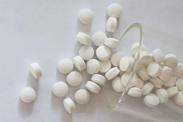 Photo of Small Round White Pills Spilled from a Jar