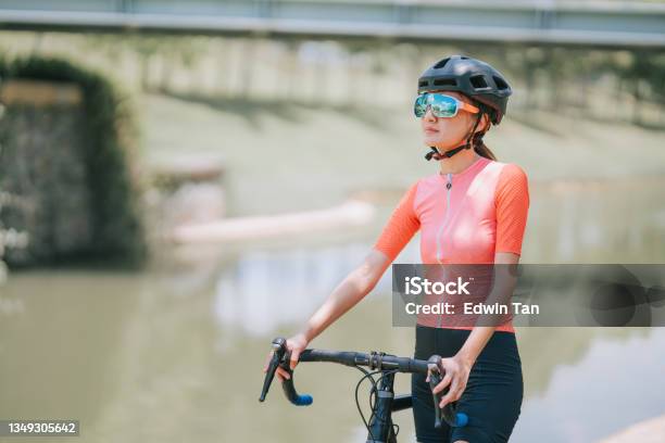 Portrait Asian Chinese Female Cyclist Standing With Road Bike During Weekend Morning At Rural Scene Looking Away With Cool Attitude Stock Photo - Download Image Now
