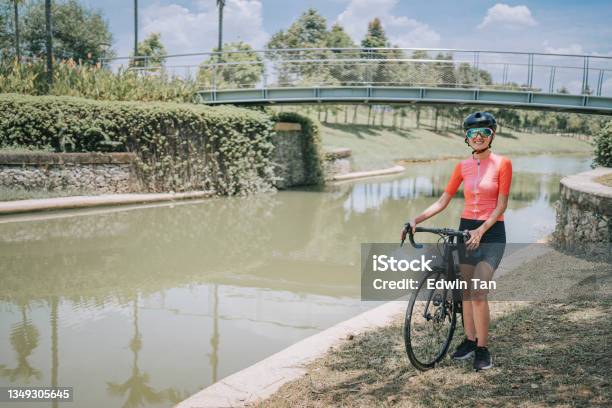 Portrait Asian Chinese Female Cyclist Standing With Road Bike During Weekend Morning At Rural Scene Looking At Camera Smiling Stock Photo - Download Image Now