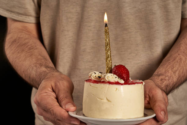 istock man's hands bringing a cheesecake to celebrate a birthday with a lit candle 1349307586