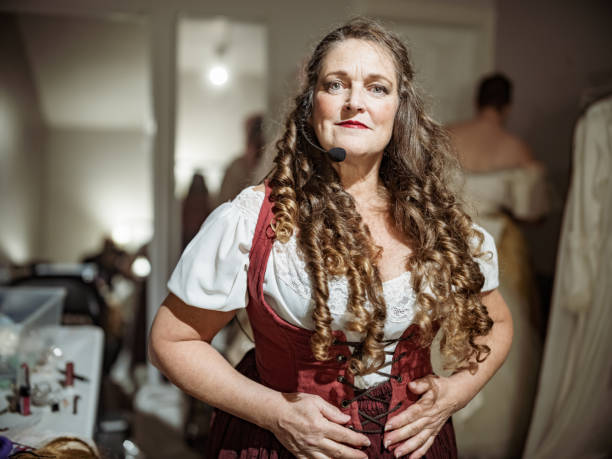 Studio portrait of a woman in her 20s with flawless skin and natural freckles looking at camera in a red studio, embodying self-confidence, poise, and feminine poise.
