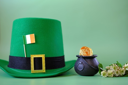 St.Patrick 's Day.Green leprechaun hat, flag of Ireland, bowler hat with gold coins, bunch of clovers on a green background. Saint Patrick holiday. St patrick's day background.