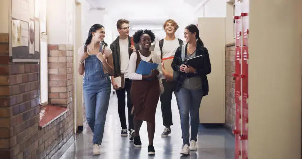 Photo of Shot of a group of teenagers walking down the hall at high school