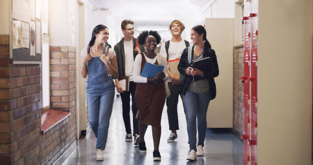 shot of a group of teenagers walking down the hall at high school - high school student imagens e fotografias de stock