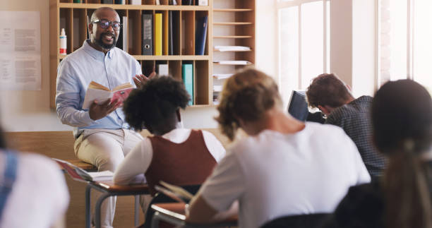 istock Shot of man reading a book to his students in a classroom 1349310048