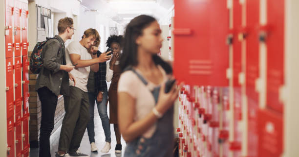 Shot of a teenage girl standing next to her locker and being bullied at high school Be a friend, not a bully exclusion group of people separation fish out of water stock pictures, royalty-free photos & images