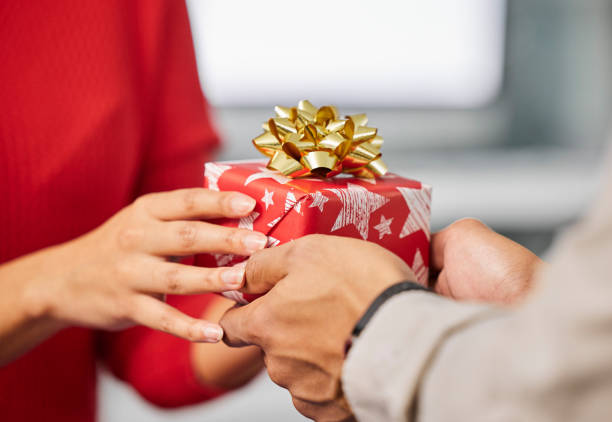 photo d’un homme d’affaires et d’une femme d’affaires méconnaissable échangeant des cadeaux de noël dans un bureau moderne - christmas office gift people photos et images de collection