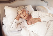 Shot of a senior woman experiencing chest pain in bed in a nursing home